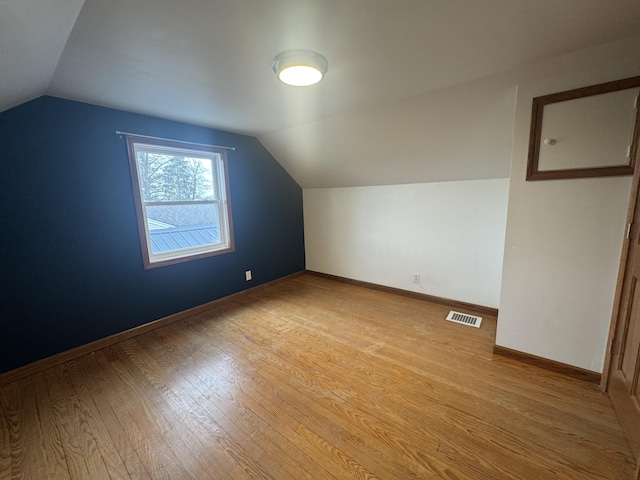 bonus room featuring baseboards, visible vents, light wood-style flooring, and lofted ceiling