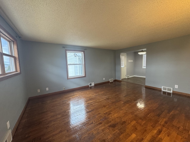 empty room with baseboards, visible vents, and wood finished floors