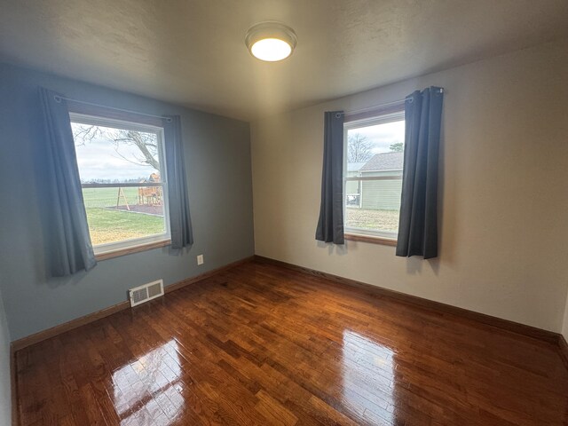 spare room featuring dark wood-style floors, baseboards, and visible vents