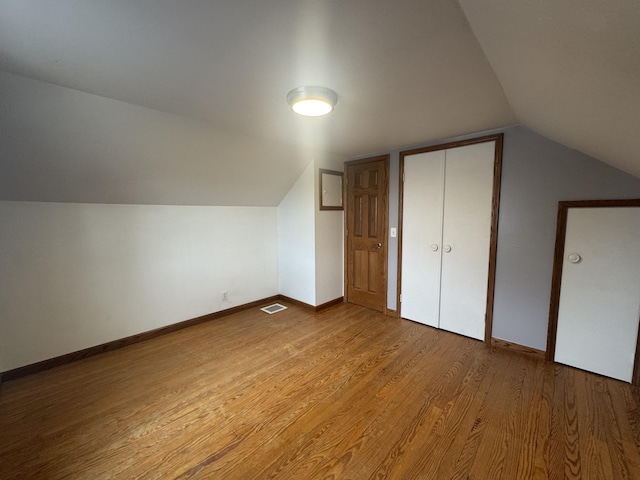 bonus room featuring baseboards, visible vents, lofted ceiling, and light wood-type flooring