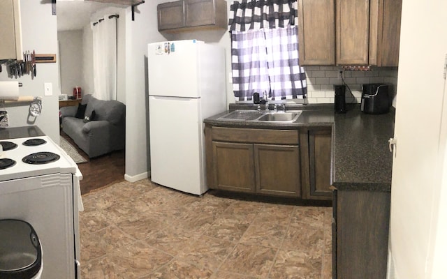 kitchen featuring dark countertops, decorative backsplash, freestanding refrigerator, a sink, and range with electric cooktop