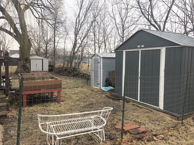 view of yard with a storage shed, an outdoor structure, a vegetable garden, and fence