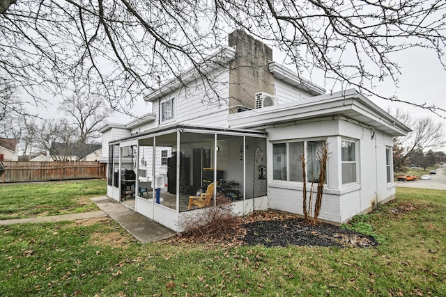 rear view of property with a sunroom and a lawn