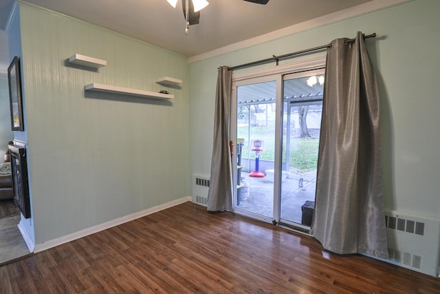 spare room featuring dark hardwood / wood-style flooring, radiator, and ceiling fan