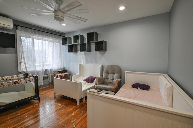 bedroom with dark hardwood / wood-style floors, a wall mounted AC, and ceiling fan