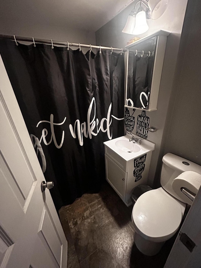 full bathroom featuring curtained shower, stone finish flooring, vanity, and toilet