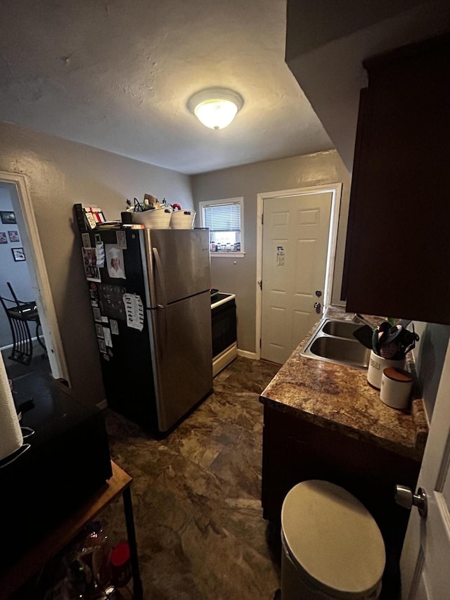 kitchen featuring freestanding refrigerator, a sink, and range with electric cooktop