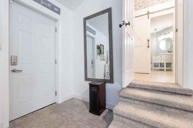 entryway with carpet flooring, baseboards, and a barn door