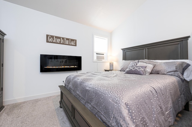 bedroom with a glass covered fireplace, cooling unit, carpet floors, baseboards, and vaulted ceiling