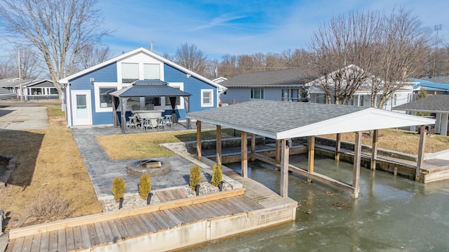 view of dock with a fire pit, a water view, a gazebo, a yard, and a patio