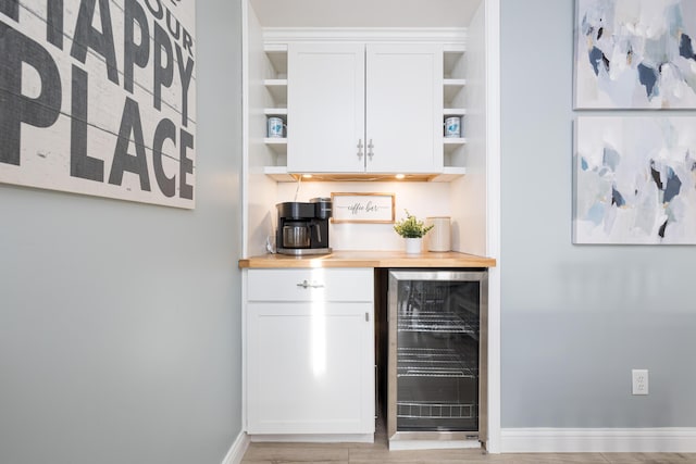 bar featuring a dry bar, beverage cooler, and baseboards