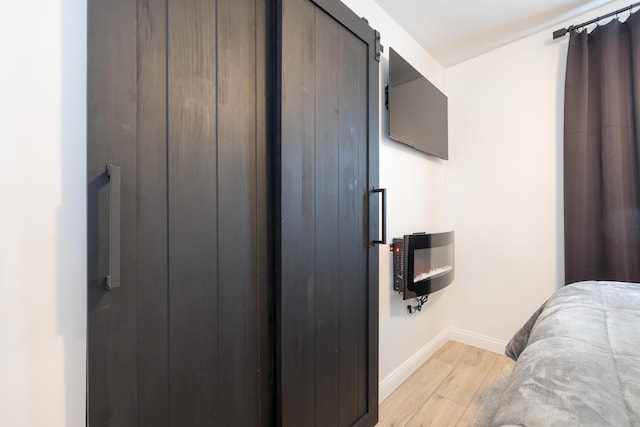 bedroom featuring baseboards, light wood-style floors, and a barn door