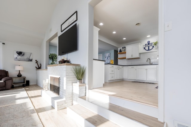 living area featuring recessed lighting, visible vents, light wood-style floors, and a fireplace