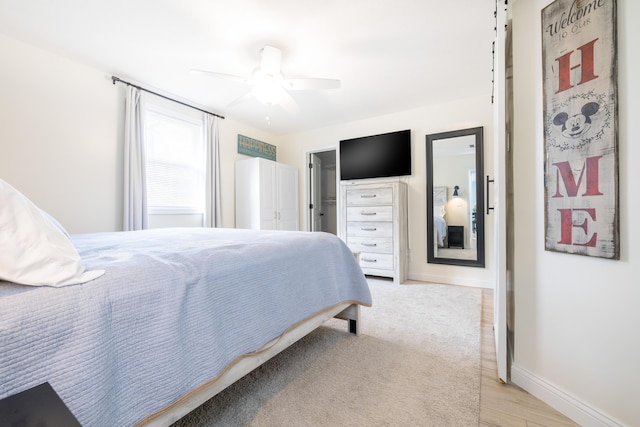 bedroom with light wood finished floors, a ceiling fan, and baseboards