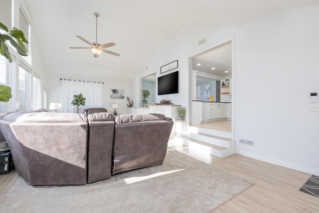 living area featuring visible vents, high vaulted ceiling, baseboards, and wood finished floors