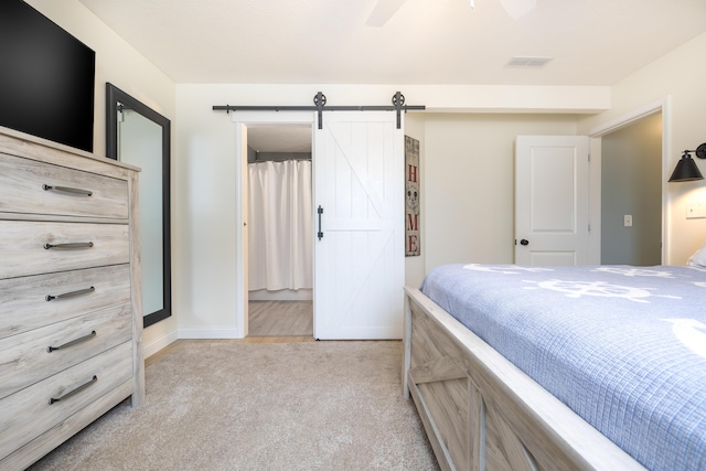 bedroom featuring a ceiling fan, visible vents, baseboards, a barn door, and light colored carpet