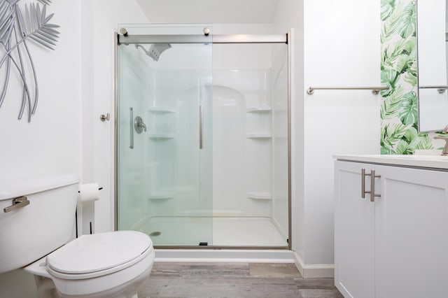 bathroom featuring toilet, wood finished floors, and a shower stall