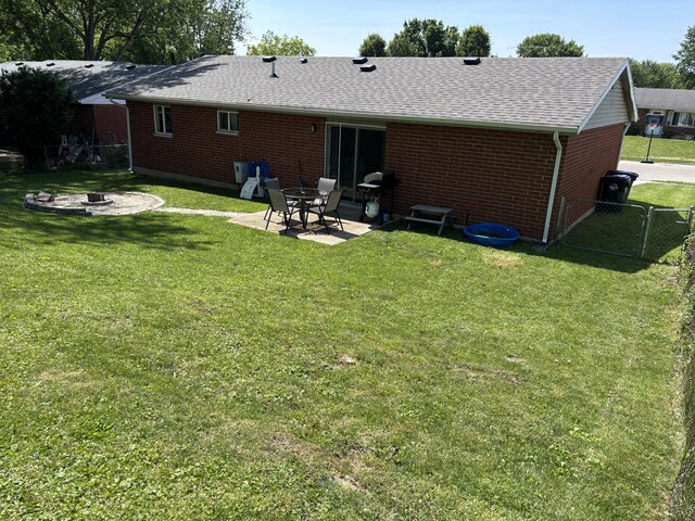 1353 Lee Rd, Troy, OH 45373 - back of property with a fire pit, roof with shingles, brick siding, and a patio