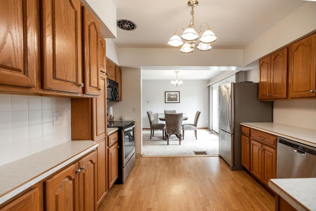 1706 N Fountain Blvd, Springfield, OH 45504 - kitchen featuring stainless steel appliances, a chandelier, brown cabinets, and light countertops
