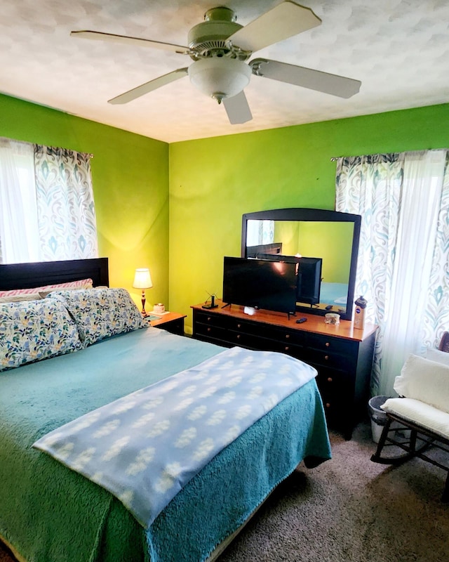 carpeted bedroom with multiple windows and ceiling fan