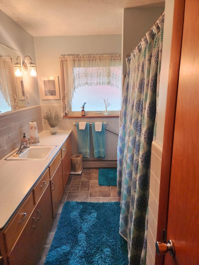 bathroom featuring vanity, baseboard heating, backsplash, and stone finish flooring