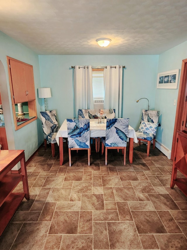 dining room with stone finish flooring, baseboards, and a baseboard heating unit