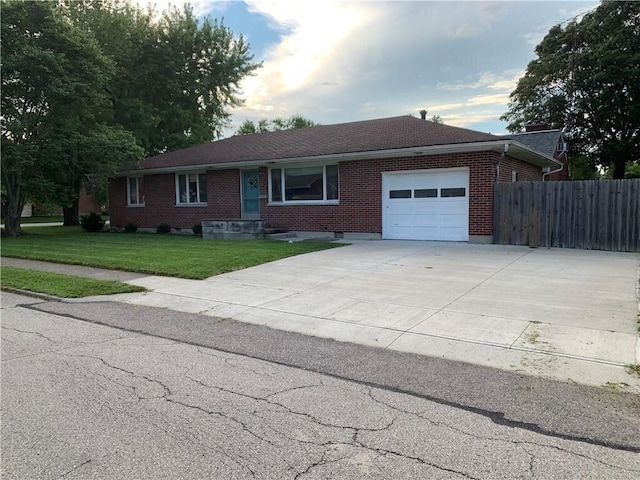 ranch-style home with fence, a front lawn, brick siding, a garage, and driveway