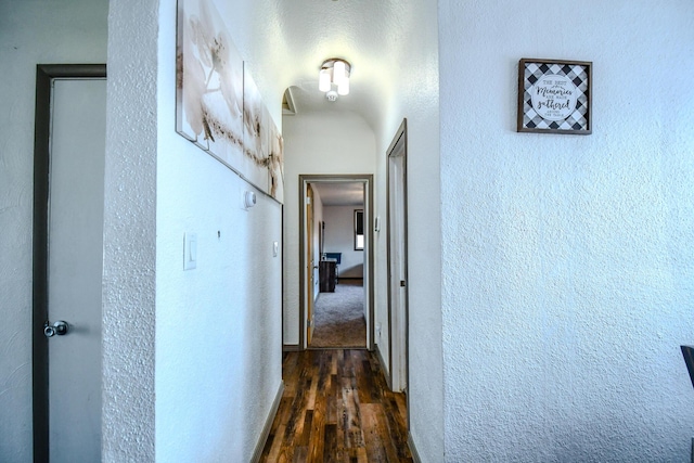 corridor with dark wood-style floors and a textured wall