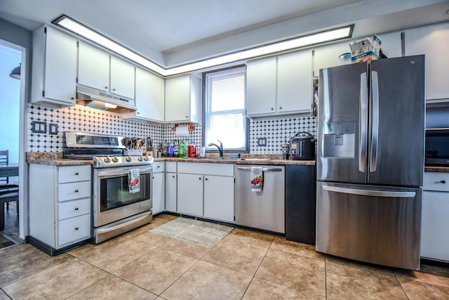 kitchen featuring dark countertops, under cabinet range hood, tasteful backsplash, and appliances with stainless steel finishes