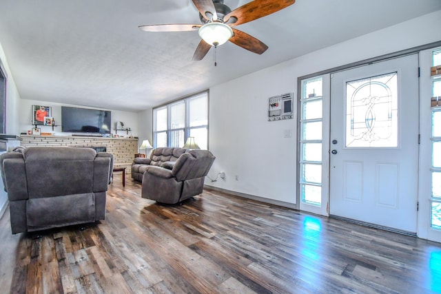 living room featuring ceiling fan, baseboards, and dark wood-style flooring