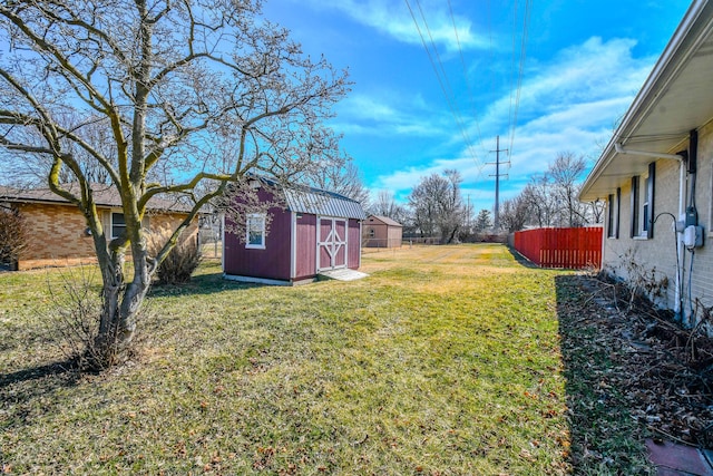 view of yard featuring fence, a storage unit, and an outbuilding