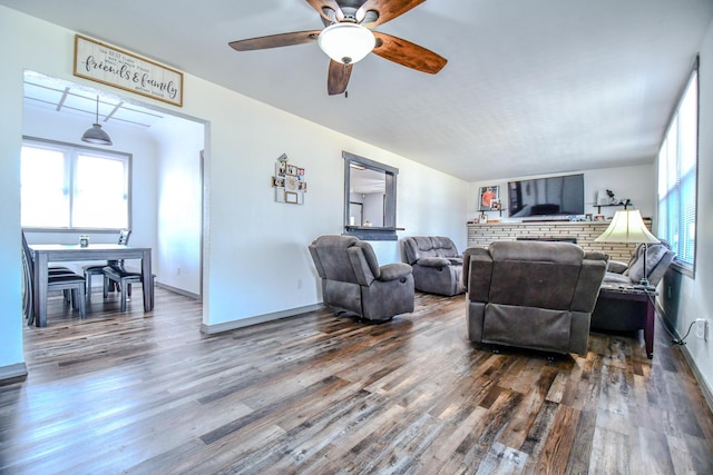 living room featuring a ceiling fan, baseboards, and wood finished floors