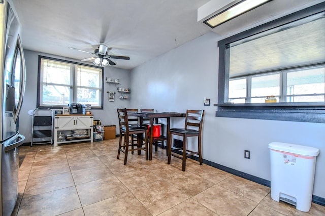 dining space with ceiling fan, baseboards, and tile patterned floors