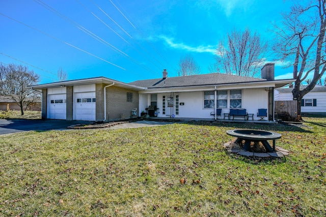 single story home featuring driveway, a garage, a fire pit, and a front yard