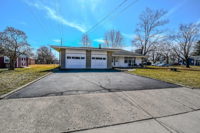 exterior space with an attached garage, driveway, a chimney, and a front lawn