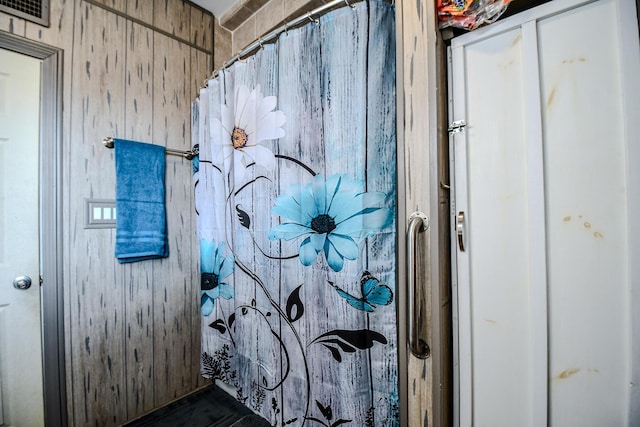 bathroom featuring curtained shower and wooden walls