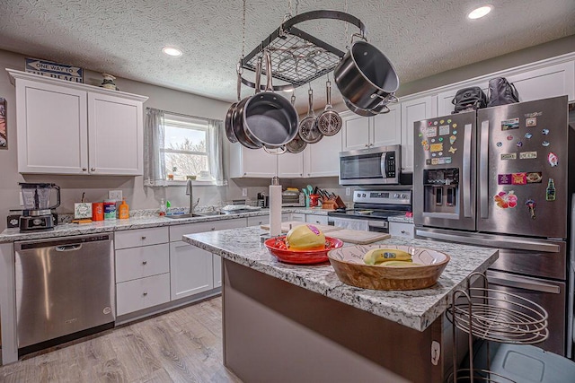 1313 Arrowhead, Piqua, OH 45356 - kitchen featuring appliances with stainless steel finishes, white cabinets, a textured ceiling, a center island, and a kitchen bar