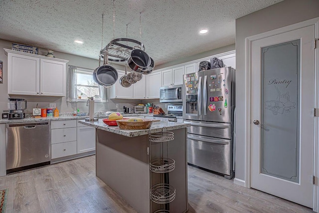 1313 Arrowhead, Piqua, OH 45356 - kitchen featuring stainless steel appliances, light wood-type flooring, a center island, white cabinetry, and a textured ceiling