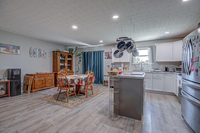 1313 Arrowhead, Piqua, OH 45356 - kitchen with stainless steel fridge with ice dispenser, light wood-type flooring, a kitchen island, recessed lighting, and white cabinets