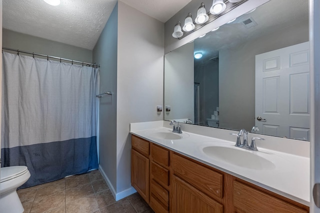 bathroom with a sink, a textured ceiling, toilet, and double vanity