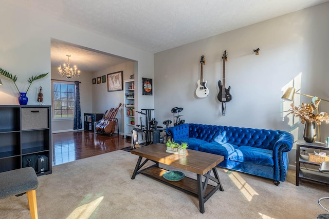 carpeted living room featuring baseboards, a chandelier, and a textured ceiling