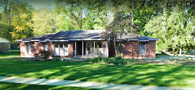 ranch-style house with a trampoline, covered porch, brick siding, and a front lawn