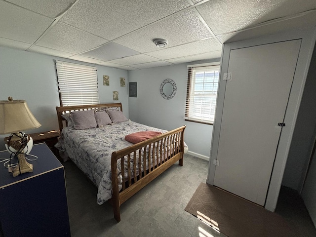 bedroom featuring electric panel, a drop ceiling, and baseboards