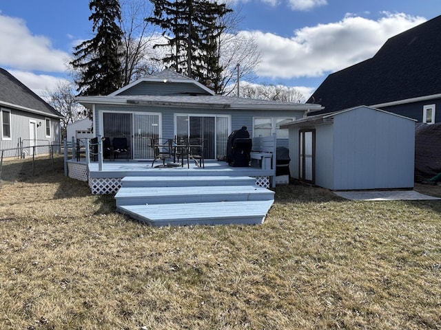 rear view of house featuring a deck, an outbuilding, a lawn, and a storage shed