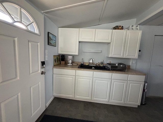 kitchen with dark wood finished floors, vaulted ceiling, white cabinets, and a sink