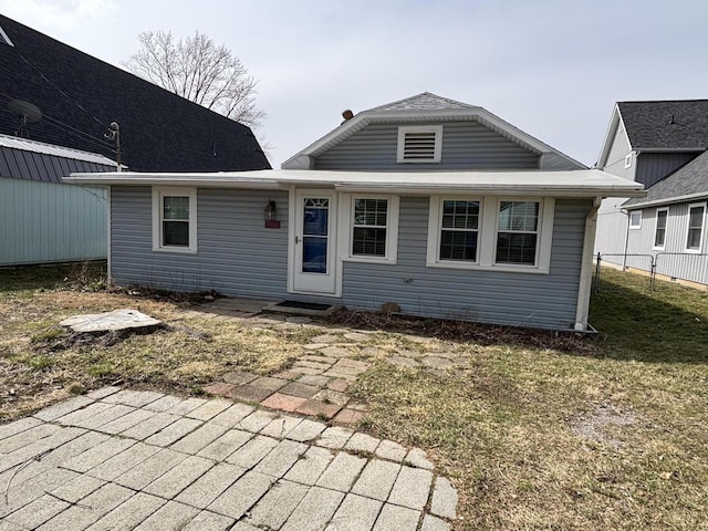 rear view of property featuring a yard and fence