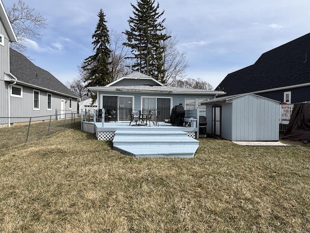 back of house featuring a lawn, an outdoor structure, a storage shed, and fence