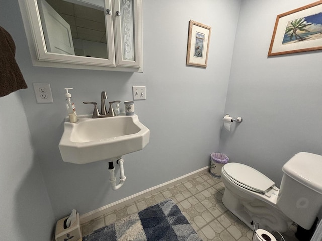 bathroom with tile patterned floors, toilet, baseboards, and a sink