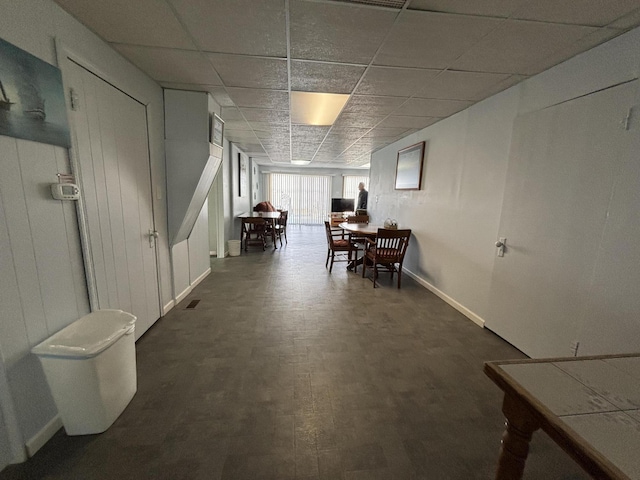 dining area featuring a drop ceiling, baseboards, and dark wood-type flooring