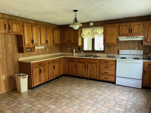 9050 N State Route 49, Greenville, OH 45331 - kitchen with white electric stove, under cabinet range hood, brown cabinetry, wooden walls, and light countertops